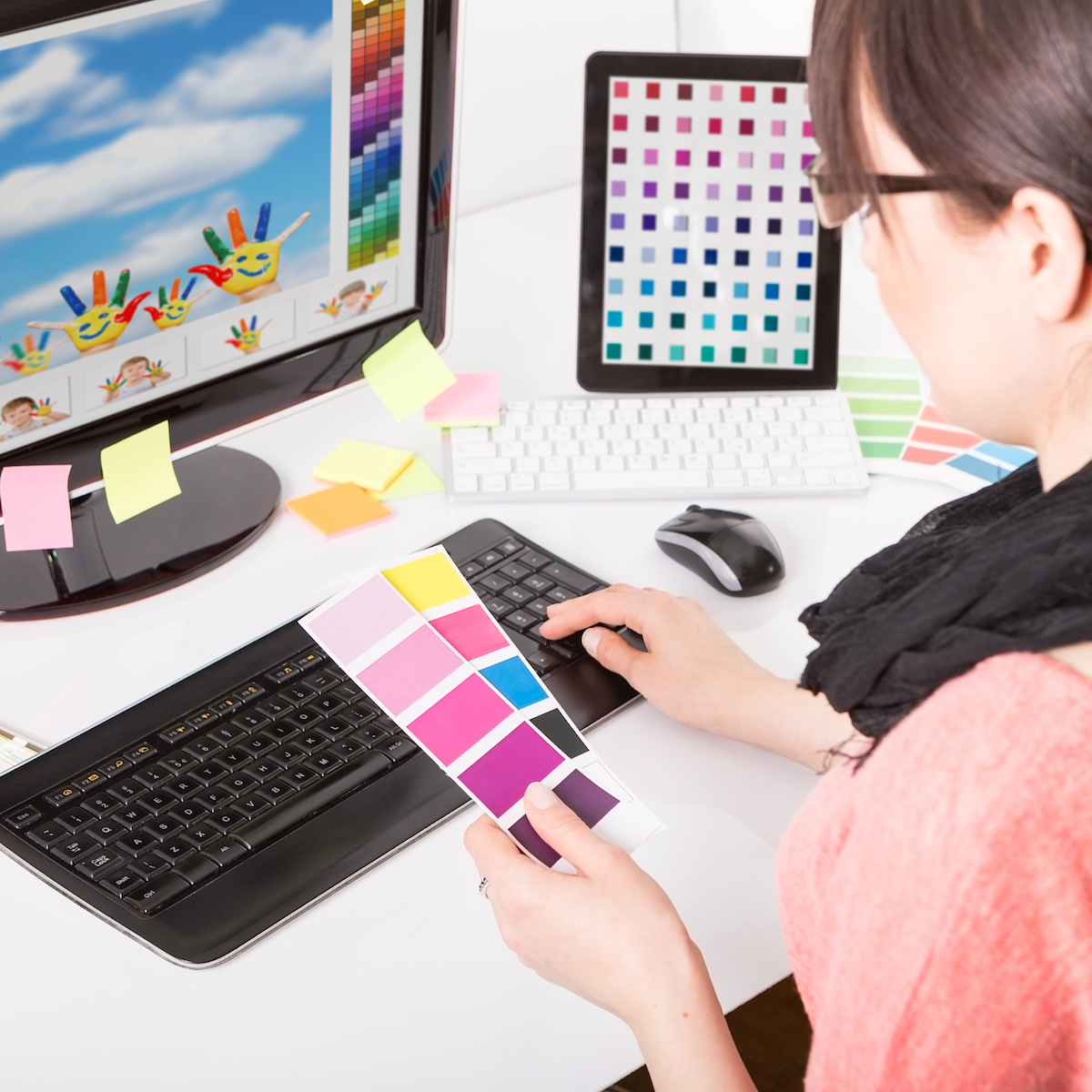 woman at a computer holding colour cards and recolouring an image